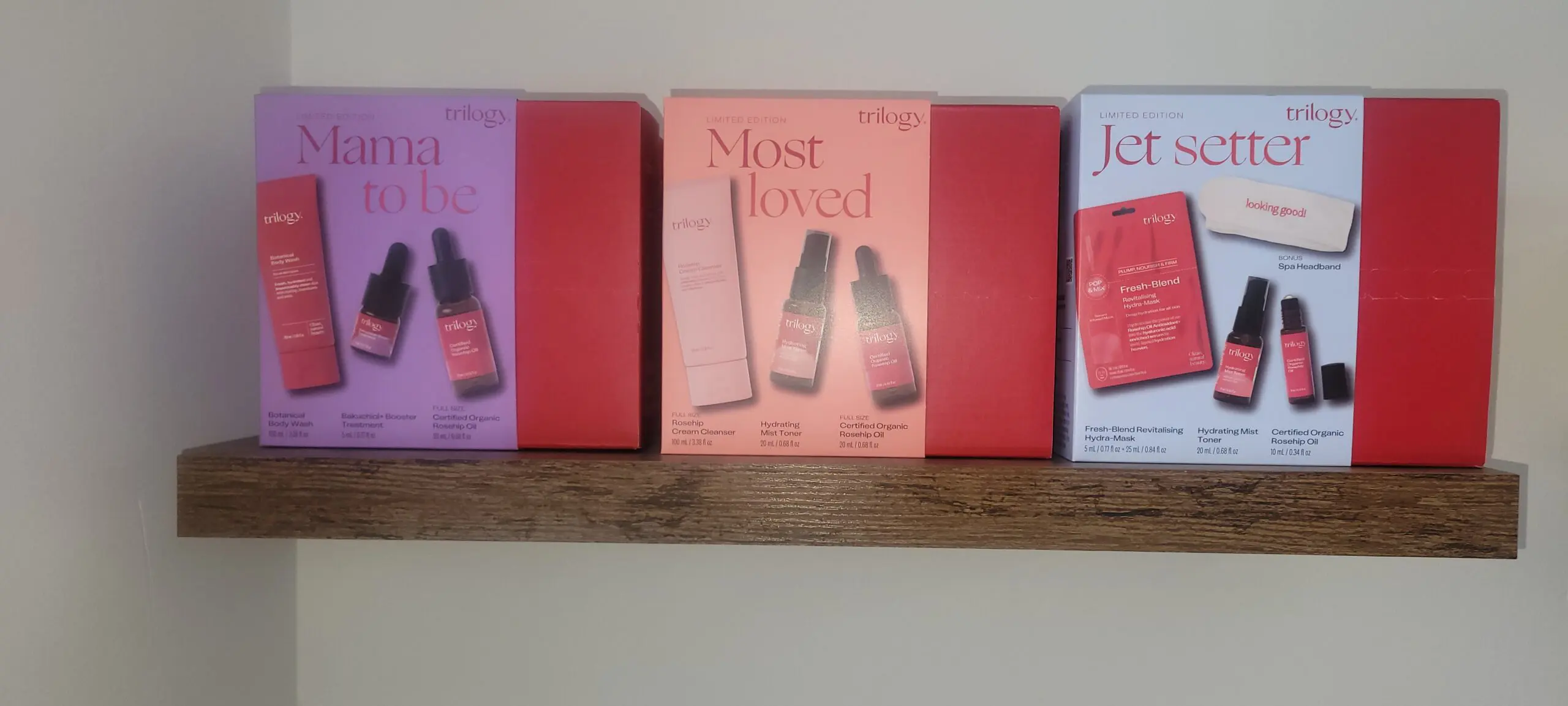 Three colorful book covers displayed on a wooden shelf.