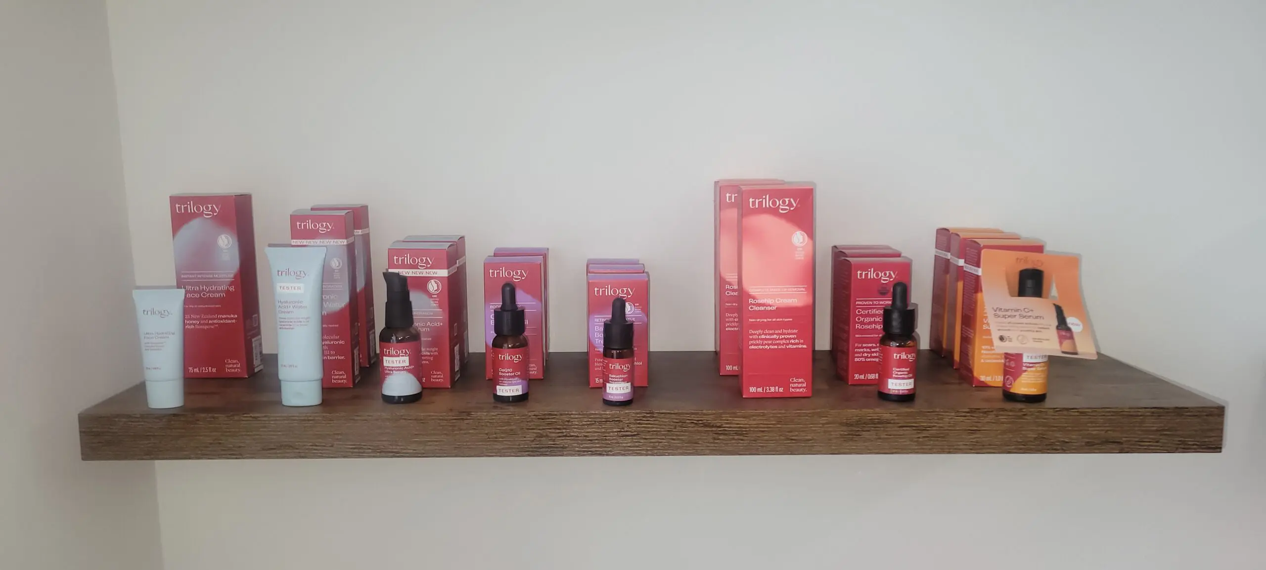 Various skincare products arranged on a wooden shelf against a plain wall.