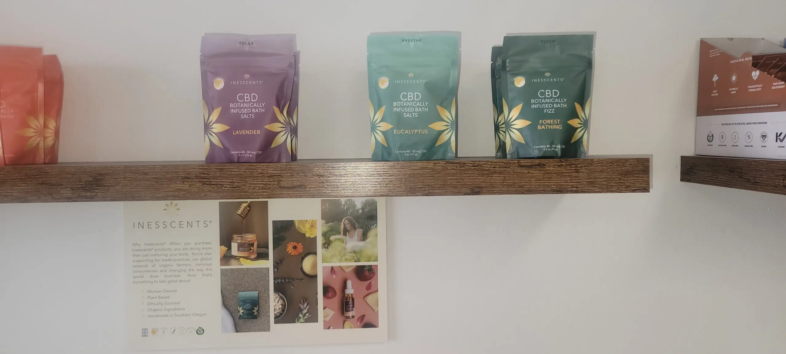 Three pastel-colored boxes and four floral postcards on a shelf against a white wall.
