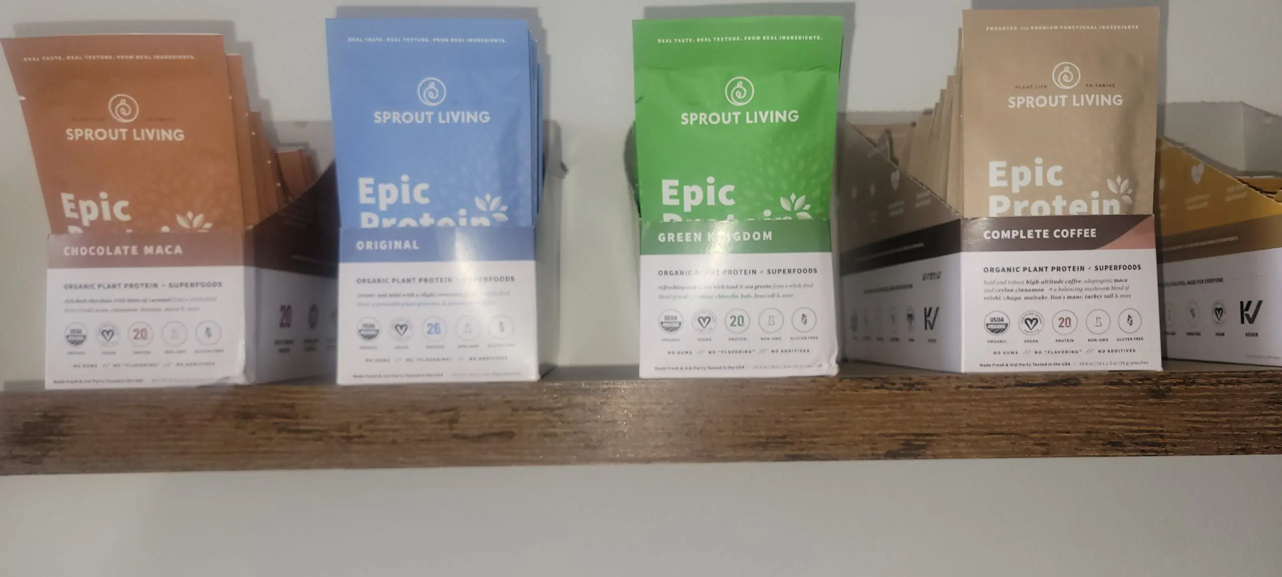 Two packages of Epic bars on a wooden shelf, one blue and one green.