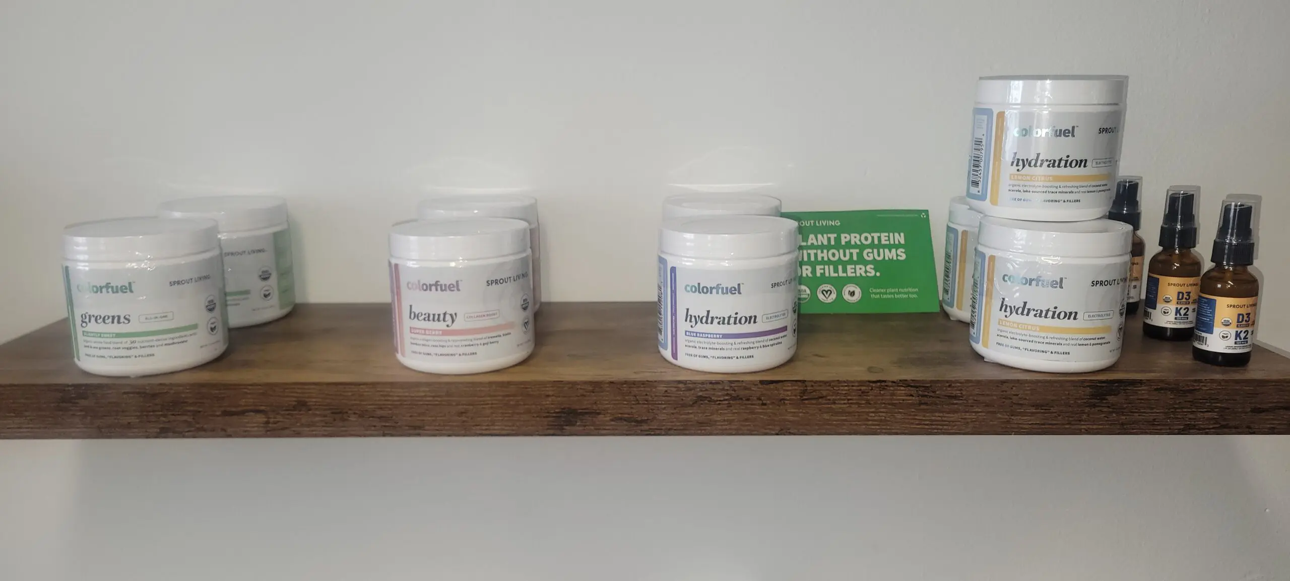 Two jars of supplements on a wooden shelf against a white wall.