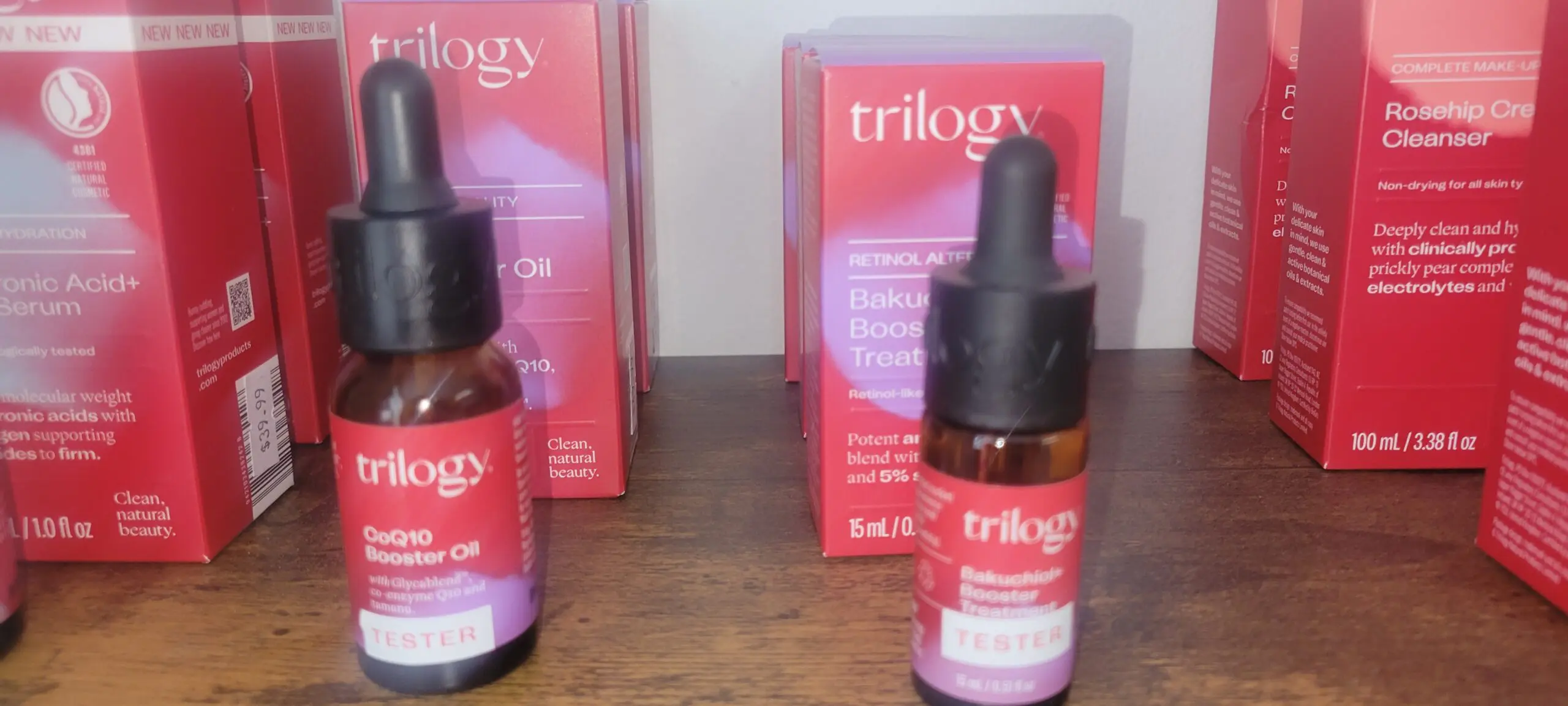 Trilogy Rosehip Oil bottles with packaging on a wooden surface.
