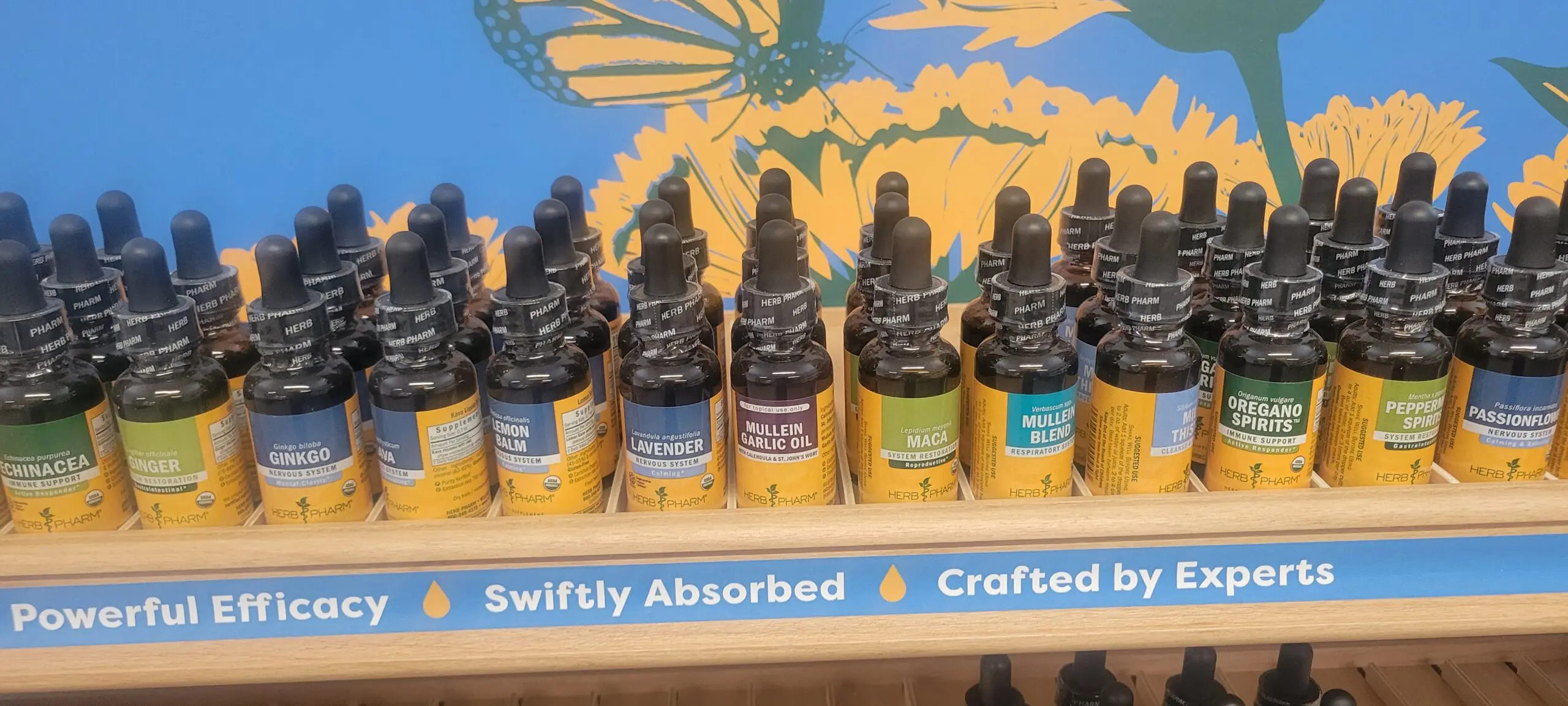 Bottles of essential oils on a wooden shelf labeled "Swiftly Absorbed" and "Crafted by Nature."