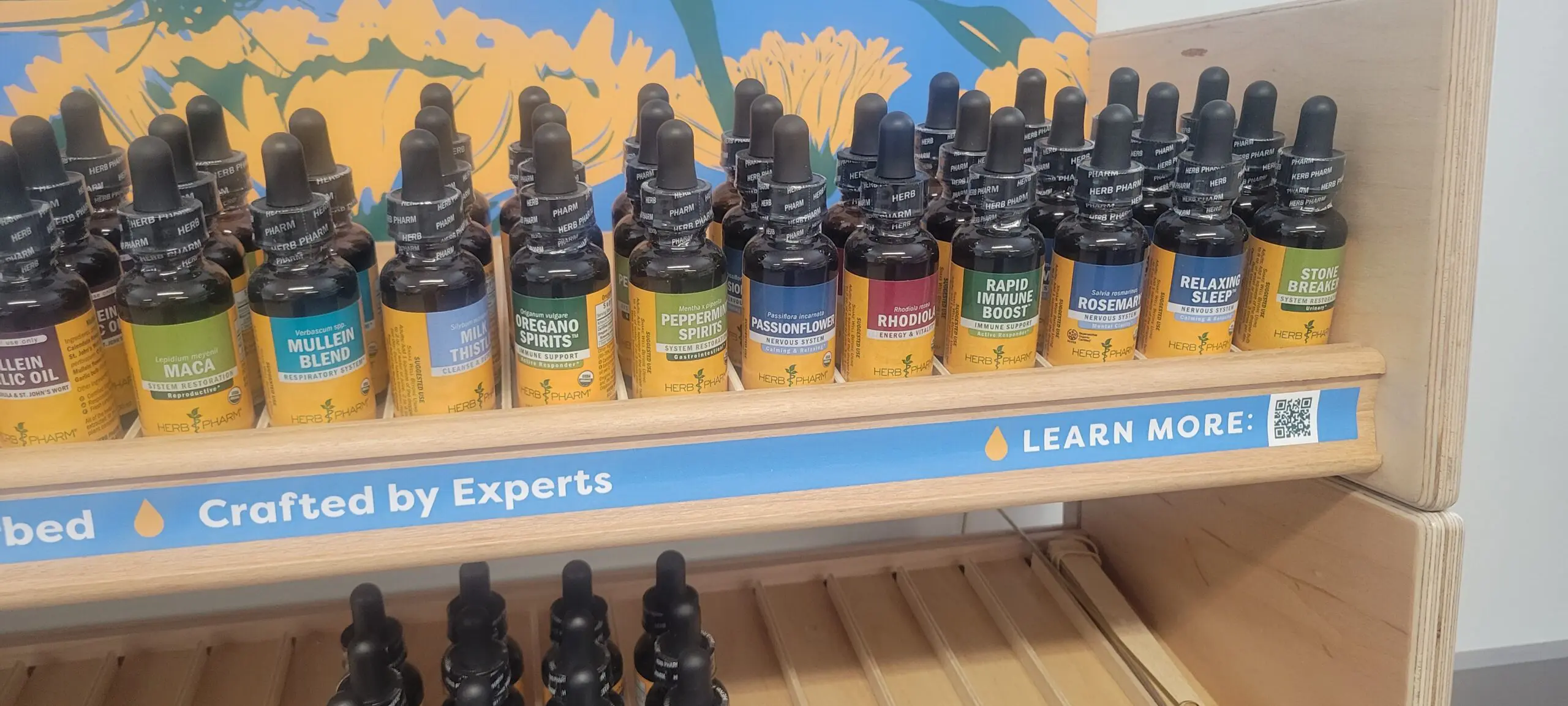 Rows of colorful essential oil bottles on a wooden shelf.