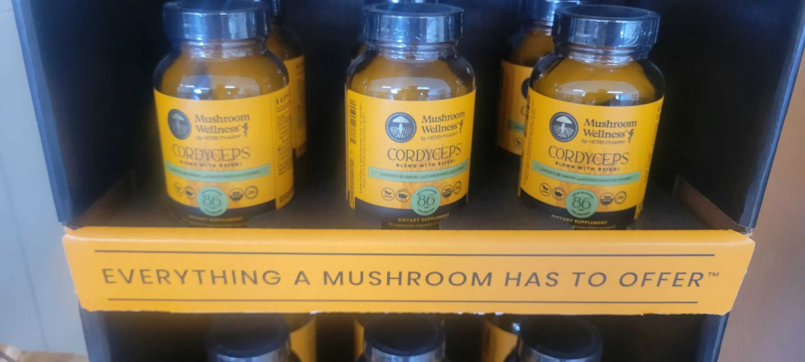 Jars of turmeric powder on a shelf with a sign about mushrooms.