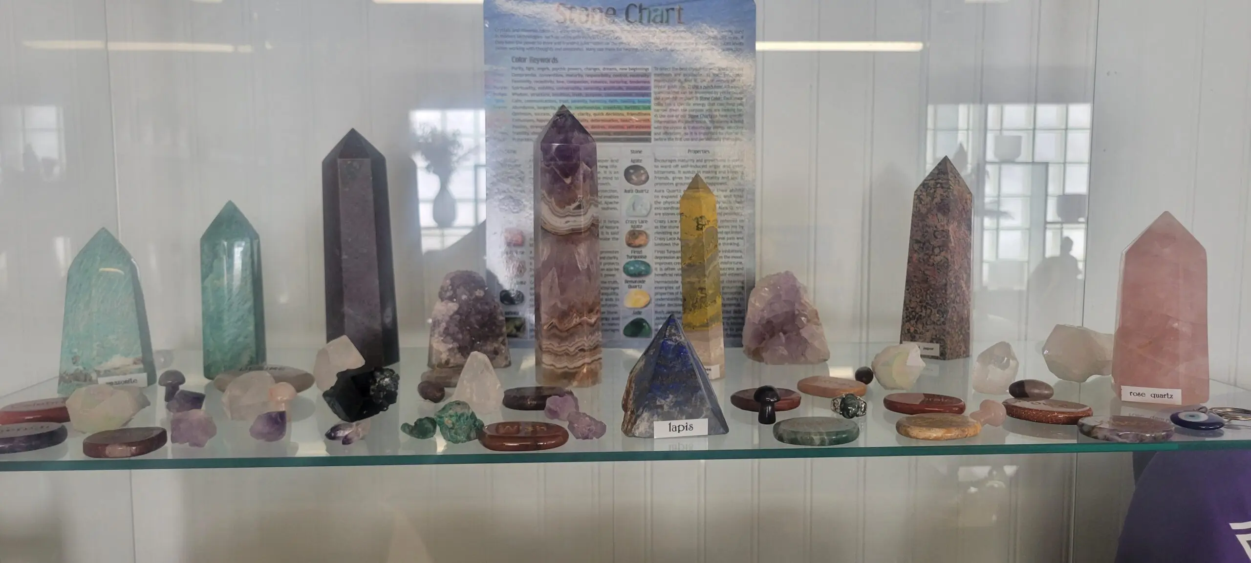 Display of colorful crystals and gemstones on a glass shelf.