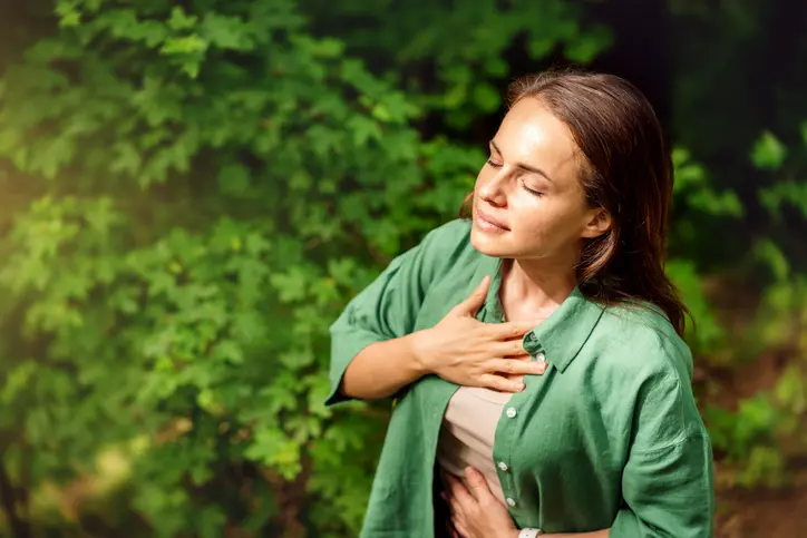 Woman with closed eyes enjoying nature's tranquility.