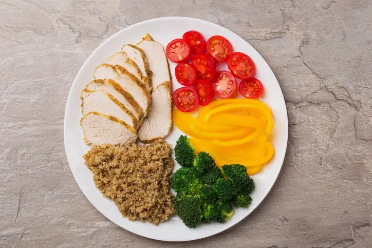 Sliced chicken breast with colorful vegetables and quinoa.